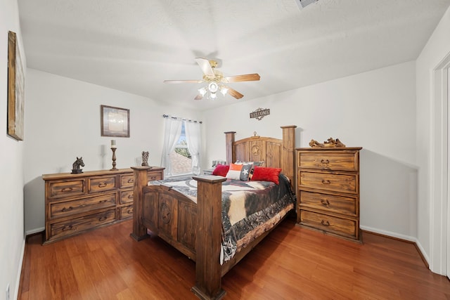 bedroom with dark hardwood / wood-style flooring and ceiling fan