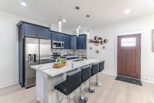 kitchen featuring light stone countertops, stainless steel appliances, sink, pendant lighting, and a breakfast bar area