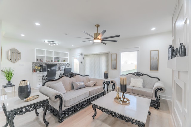 living room featuring ceiling fan, light hardwood / wood-style floors, and built in desk