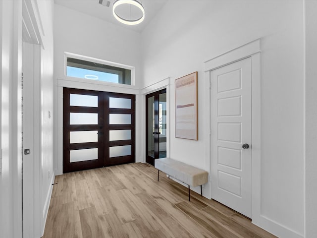 entrance foyer with french doors and light hardwood / wood-style floors