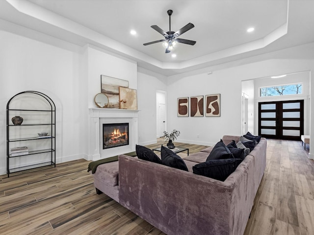 living room featuring a tray ceiling, ceiling fan, hardwood / wood-style floors, and french doors