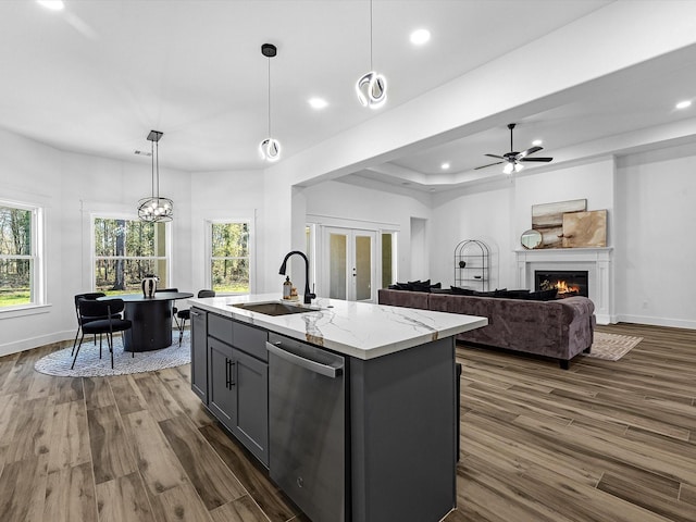 kitchen with a kitchen island with sink, sink, stainless steel dishwasher, gray cabinets, and decorative light fixtures