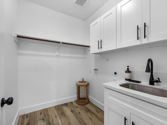 washroom with cabinets, sink, hookup for a washing machine, light hardwood / wood-style flooring, and hookup for an electric dryer