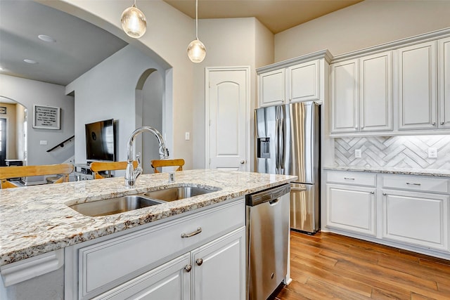 kitchen with decorative backsplash, stainless steel appliances, white cabinetry, and hanging light fixtures