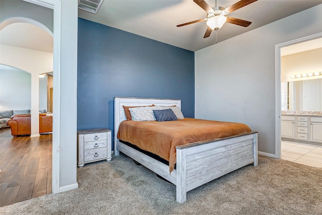 carpeted bedroom with ensuite bath and ceiling fan