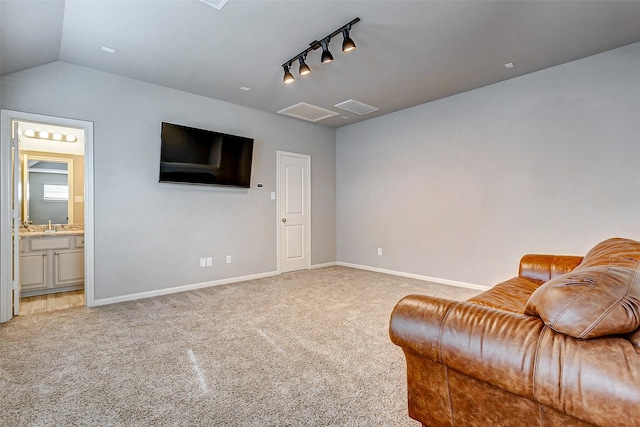 interior space featuring light colored carpet, rail lighting, and vaulted ceiling