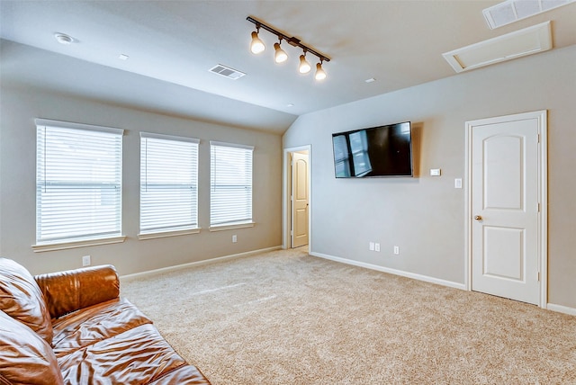 unfurnished living room with a healthy amount of sunlight, light colored carpet, lofted ceiling, and rail lighting