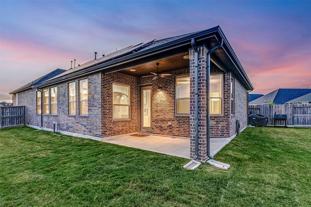 property exterior at dusk with a lawn, ceiling fan, and a patio area