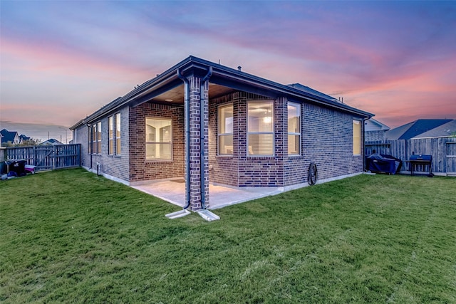 property exterior at dusk with a lawn and a patio area