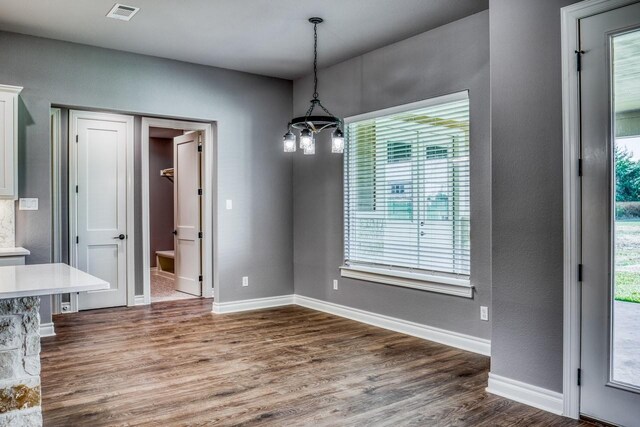 unfurnished dining area with a notable chandelier and dark hardwood / wood-style floors