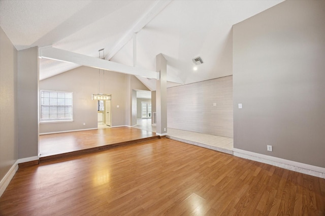 empty room with vaulted ceiling with beams and hardwood / wood-style floors