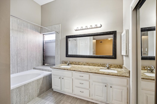 bathroom featuring tiled bath and vanity