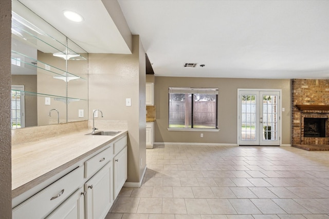 bathroom with french doors, vanity, tile patterned floors, and a brick fireplace