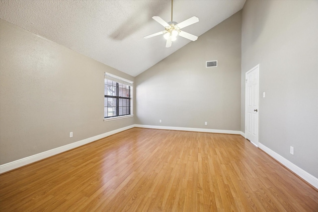 empty room with ceiling fan, light hardwood / wood-style floors, a textured ceiling, and high vaulted ceiling