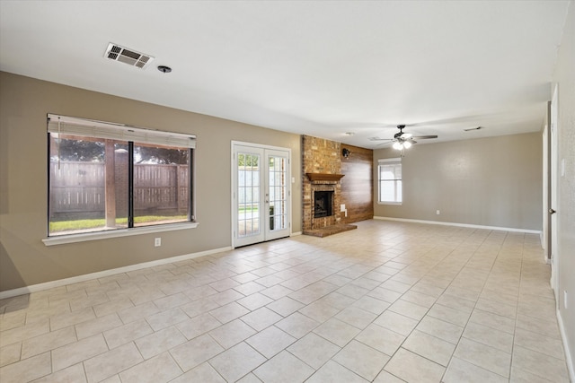 unfurnished living room with a brick fireplace, ceiling fan, light tile patterned floors, and french doors