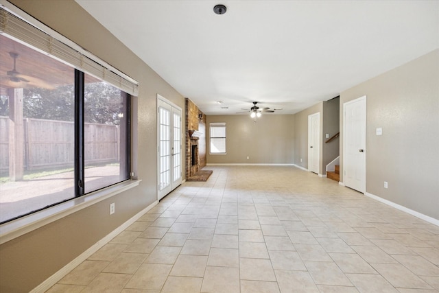 empty room featuring a fireplace, ceiling fan, and light tile patterned flooring