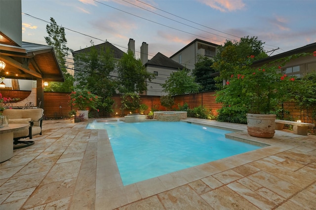 pool at dusk with pool water feature and a patio