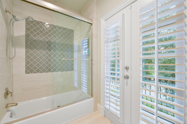 bathroom featuring a healthy amount of sunlight and bath / shower combo with glass door