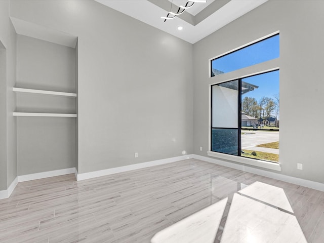 unfurnished room with built in shelves and light wood-type flooring