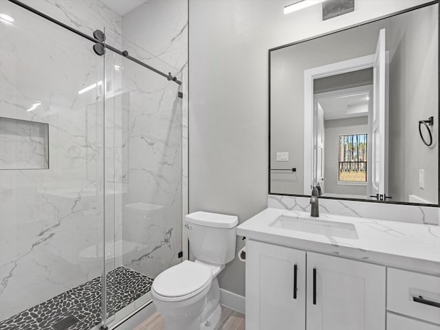 bathroom with hardwood / wood-style flooring, vanity, a shower with shower door, and toilet