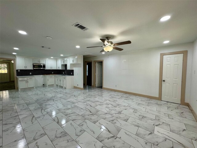 unfurnished living room with ceiling fan and sink