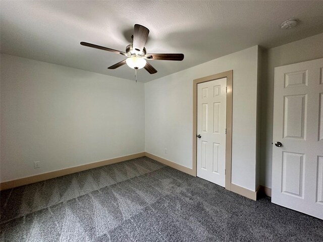 unfurnished room featuring ceiling fan and dark colored carpet