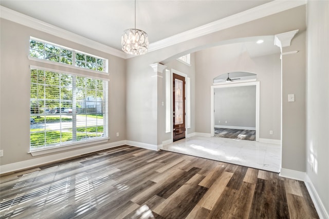 interior space with ceiling fan with notable chandelier, wood-type flooring, crown molding, and decorative columns