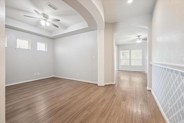 spare room with hardwood / wood-style flooring, ceiling fan, and a raised ceiling