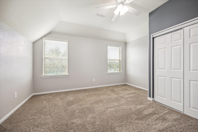 unfurnished bedroom with multiple windows, light carpet, ceiling fan, and lofted ceiling