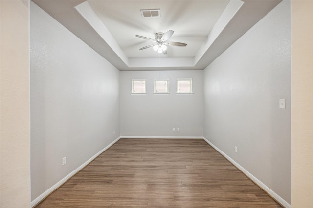 spare room featuring hardwood / wood-style floors, a raised ceiling, and ceiling fan