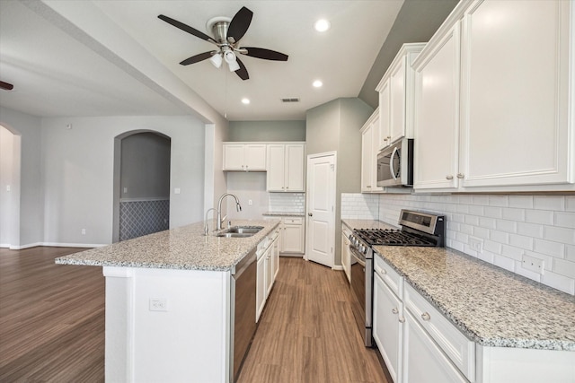 kitchen featuring light stone counters, stainless steel appliances, a kitchen island with sink, sink, and white cabinets