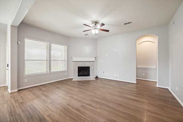 unfurnished living room featuring a tile fireplace, ceiling fan, and wood-type flooring