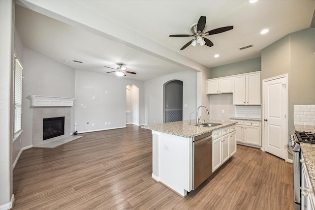 kitchen featuring sink, an island with sink, decorative backsplash, a fireplace, and appliances with stainless steel finishes