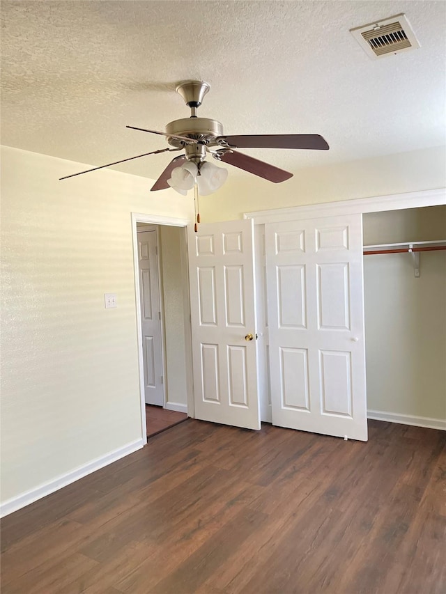 unfurnished bedroom featuring a textured ceiling, a closet, ceiling fan, and dark wood-type flooring