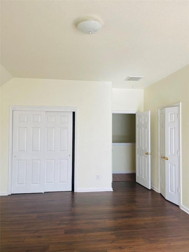 unfurnished bedroom featuring a closet and dark wood-type flooring