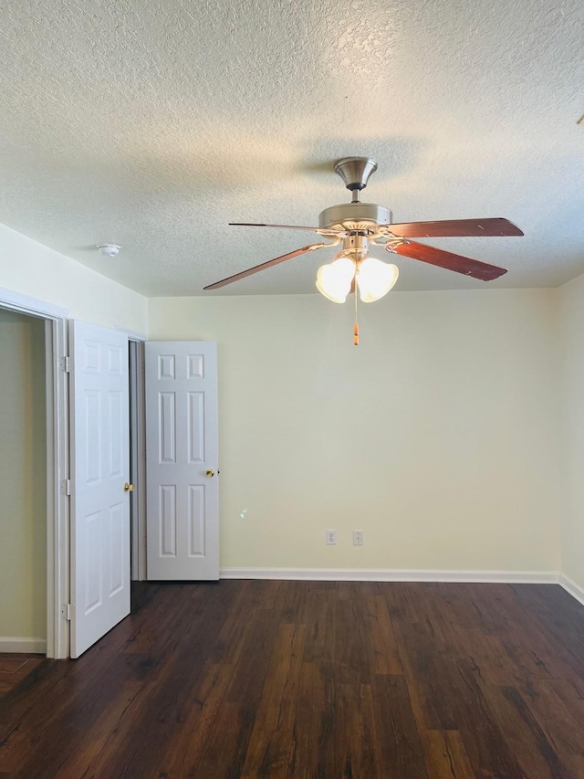 spare room featuring a textured ceiling, ceiling fan, and dark wood-type flooring