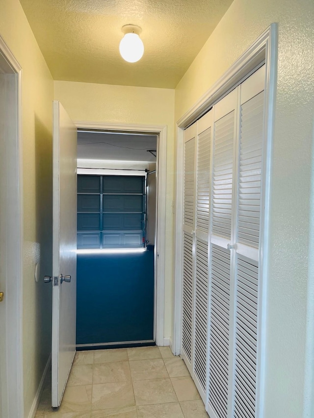 hall featuring light tile patterned floors and a textured ceiling