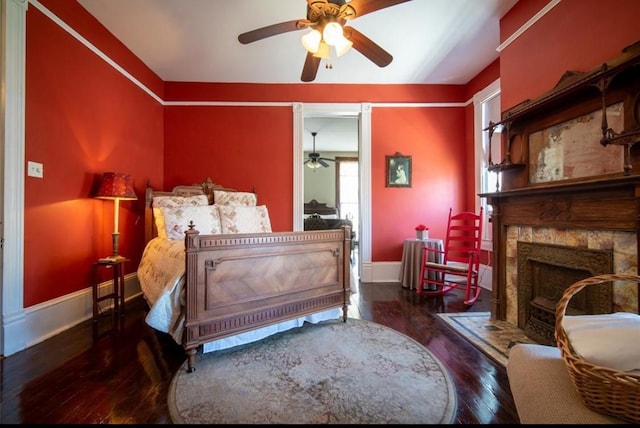 bedroom with a fireplace, ceiling fan, and dark hardwood / wood-style flooring