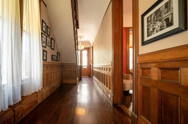 corridor with dark wood-type flooring and vaulted ceiling