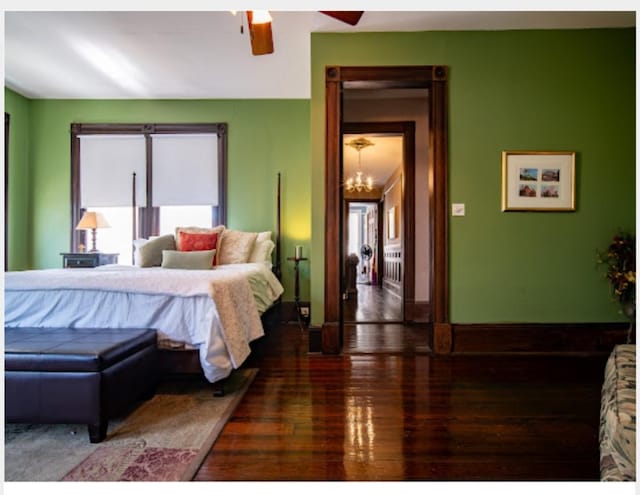 bedroom featuring ceiling fan with notable chandelier and dark hardwood / wood-style floors