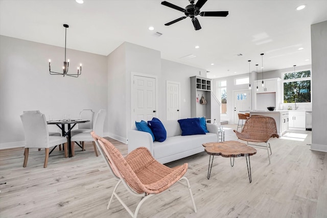 living room featuring sink, ceiling fan with notable chandelier, and light wood-type flooring