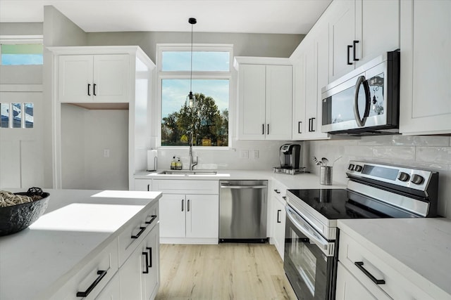 kitchen featuring backsplash, hanging light fixtures, light stone countertops, white cabinetry, and stainless steel appliances