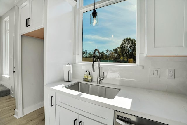 kitchen featuring dishwasher, backsplash, white cabinets, sink, and hanging light fixtures