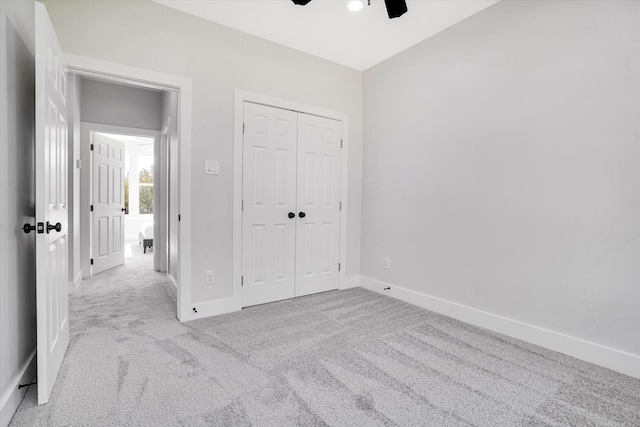 unfurnished bedroom with light carpet, a closet, and ceiling fan