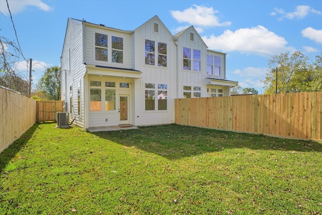 back of property with a yard and central AC