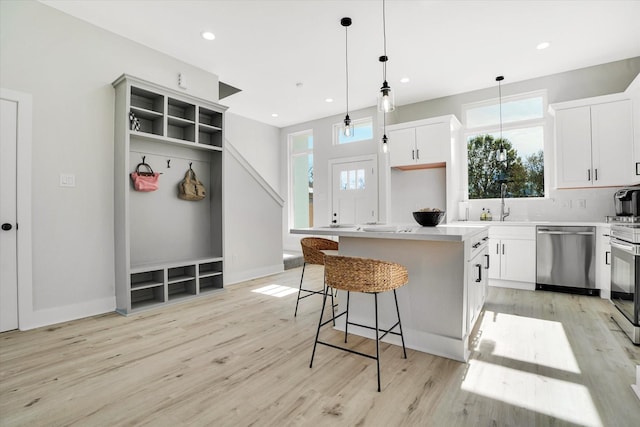 kitchen featuring white cabinets, pendant lighting, stainless steel dishwasher, and a kitchen island