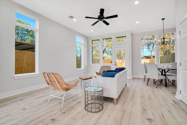 living area featuring light hardwood / wood-style floors and ceiling fan with notable chandelier