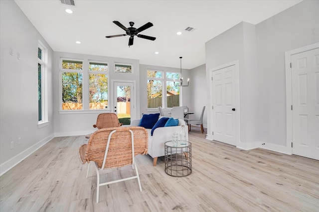 sitting room with ceiling fan with notable chandelier and light wood-type flooring