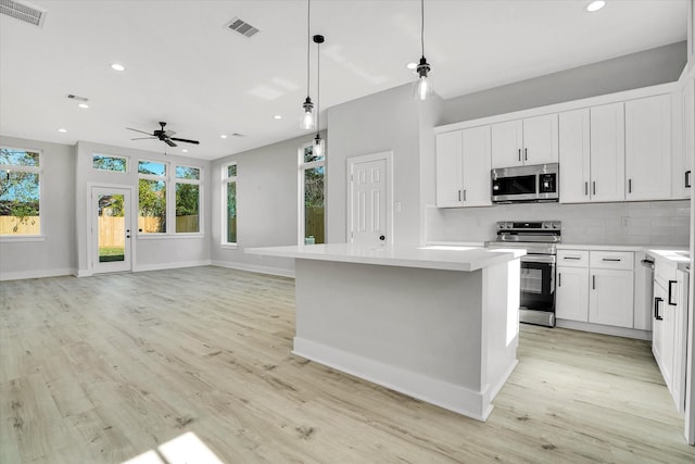 kitchen with ceiling fan, white cabinetry, pendant lighting, a kitchen island, and appliances with stainless steel finishes