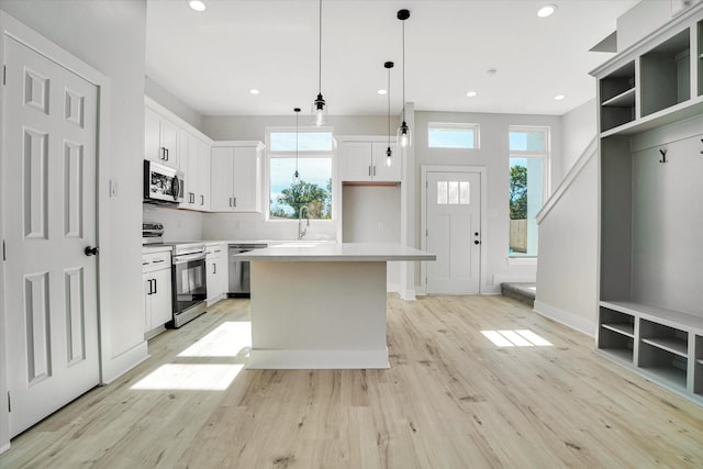 kitchen with pendant lighting, a center island, white cabinets, sink, and stainless steel appliances